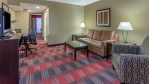 A hotel room with a red and black checkered carpet, a sofa, a chair, a desk with a computer, and two lamps. - Holiday Inn Express Hotel & Suites Bowling Green by IHG (Bowling Green)