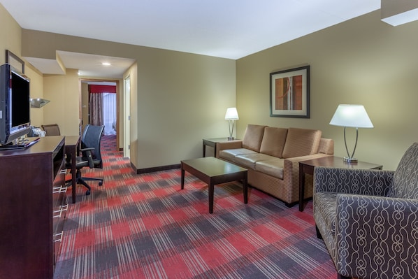 A hotel room with a red and black checkered carpet, a sofa, a chair, a desk with a computer, and two lamps. - Holiday Inn Express Hotel & Suites Bowling Green by IHG (Bowling Green)