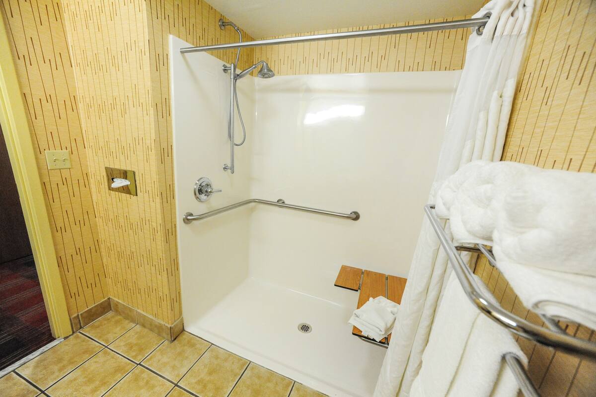 A shower area with a grab bar, a towel rack, and a wooden floor.
