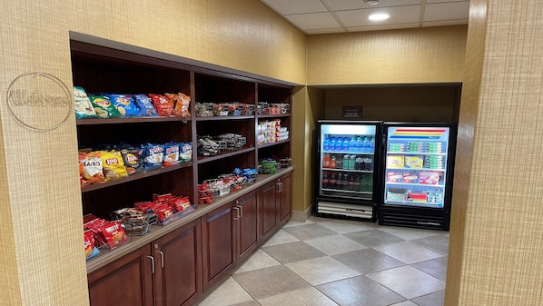 A snack and beverage area with shelves stocked with various snacks and a refrigerated display case. - Holiday Inn Express Hotel & Suites Bowling Green by IHG (Bowling Green)