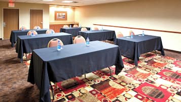 Une salle de conférence équipée de plusieurs tables, de chaises et de bouteilles d’eau.