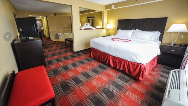 A hotel room with a large bed, a desk, a chair, a television, and a red and black checkered carpet. - Holiday Inn Express Hotel & Suites Bowling Green by IHG (Bowling Green)