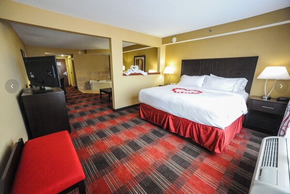 Een hotelkamer met een groot bed, een bureau, een stoel, een televisie en een zwart-rood geruit tapijt.