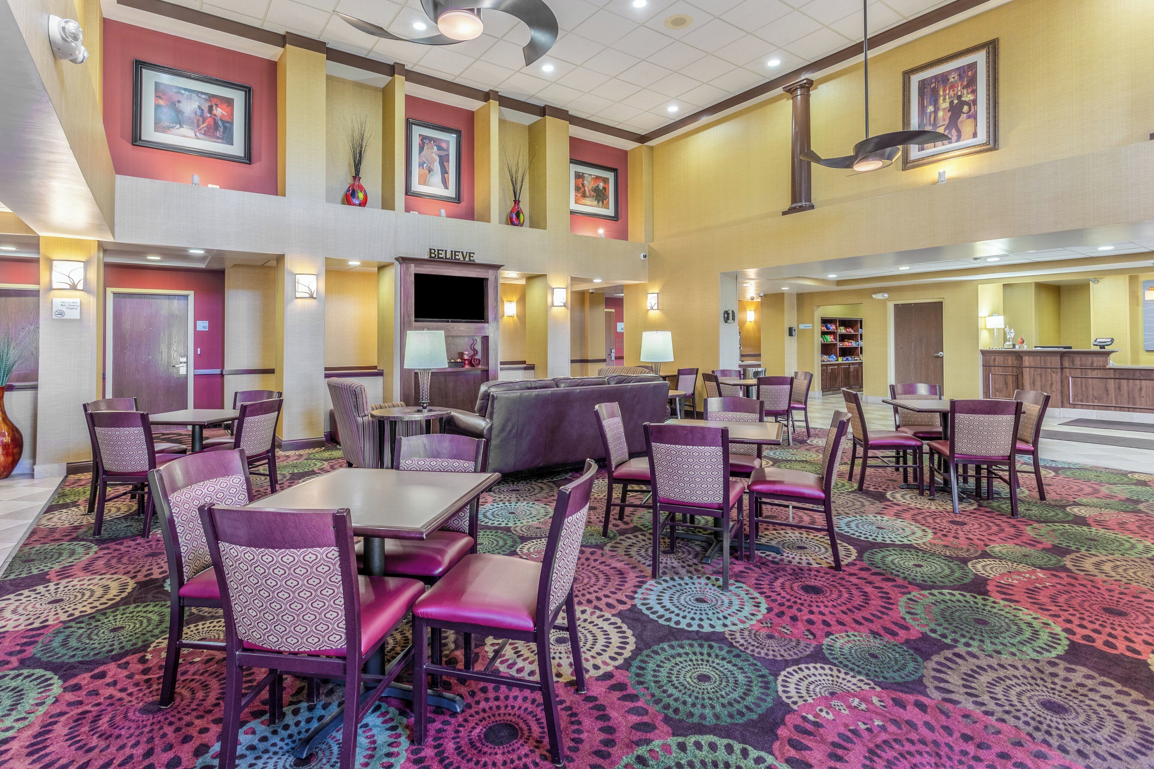 A hotel lobby with multiple seating areas, a reception desk, and artwork on the walls.