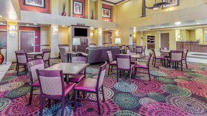 Un hall de hotel con varias zonas de estar, un mostrador de recepción y obras de arte en las paredes.