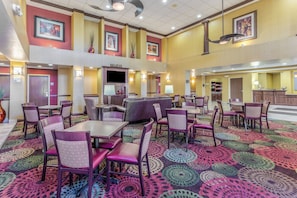 A hotel lobby with multiple seating areas, a reception desk, and artwork on the walls.