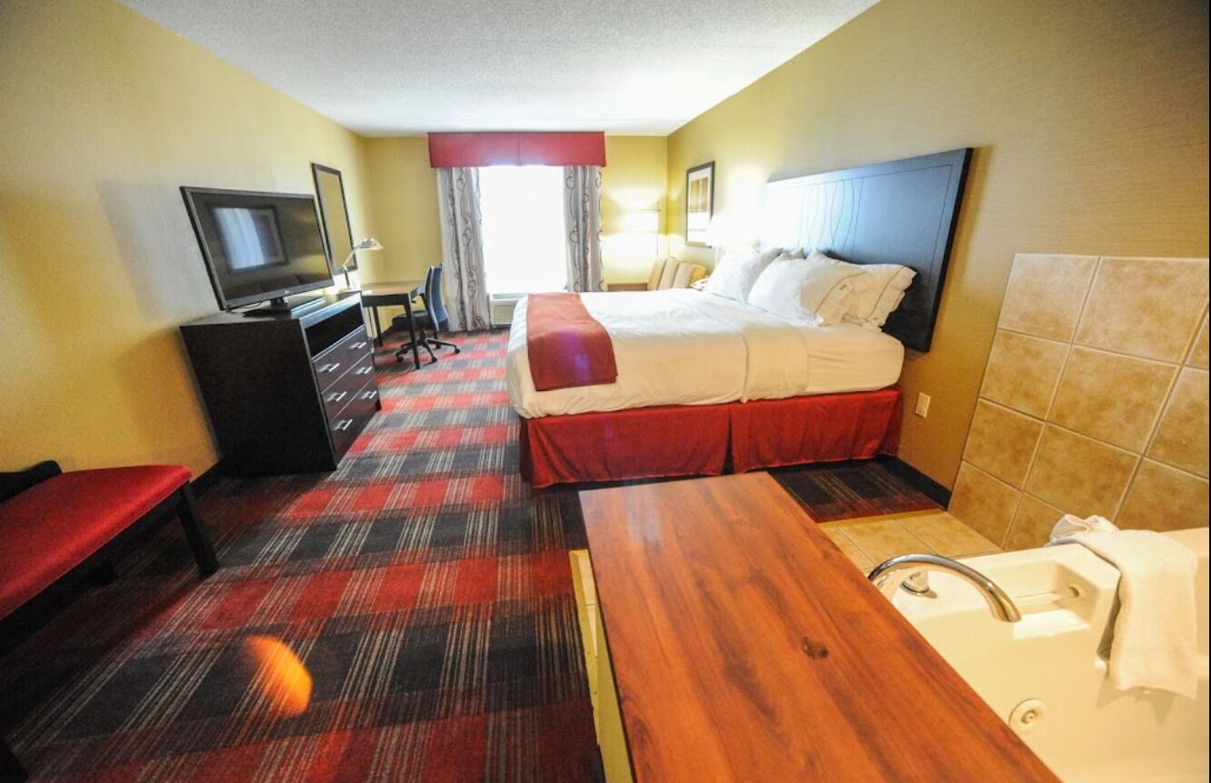 Ein Hotelzimmer mit Bett, Schreibtisch, Fernseher, Stuhl und Badezimmer.