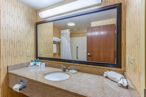 Een badkamer met een houten wand, een wastafel, een spiegel en een douche.