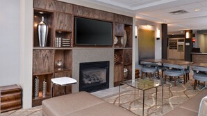 Um hall de hotel moderno com lareira, área de estar e bar.