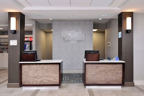 A reception desk area with two counters, a wall-mounted sign, and a Coca-Cola refrigerator in the background. - Holiday Inn Express Hotel & Suites Lafayette by IHG (Lafayette)