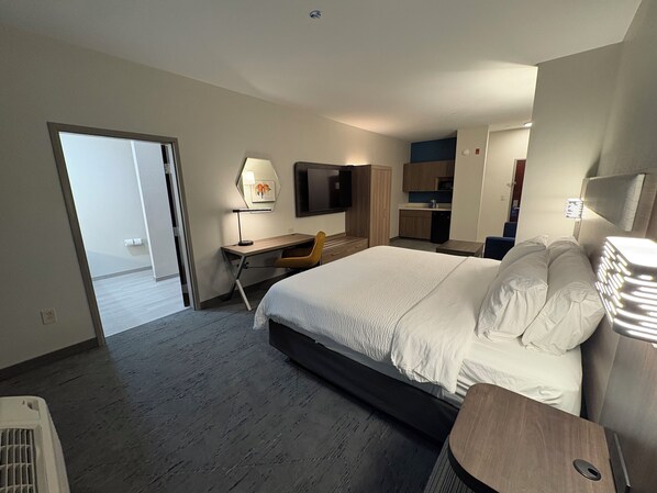 A modern hotel room with a large bed, a desk, a chair, a TV, and a kitchenette. - Holiday Inn Express Hotel & Suites Lafayette by IHG (Lafayette)