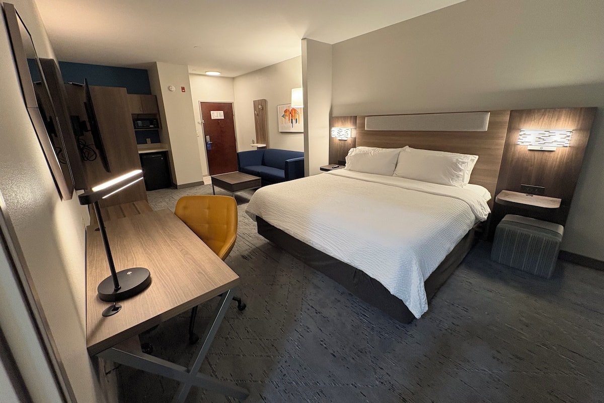 A hotel room with a bed, desk, chair, and a television.