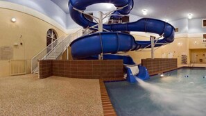 An indoor water slide with a spiral design, a pool, and a staircase leading to the slide. - Garner Hotel Brookings by IHG (Brookings)