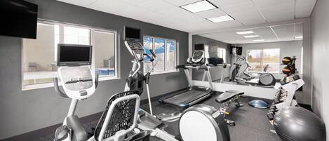 A gym with various exercise equipment, including treadmills, stationary bikes, and weights.