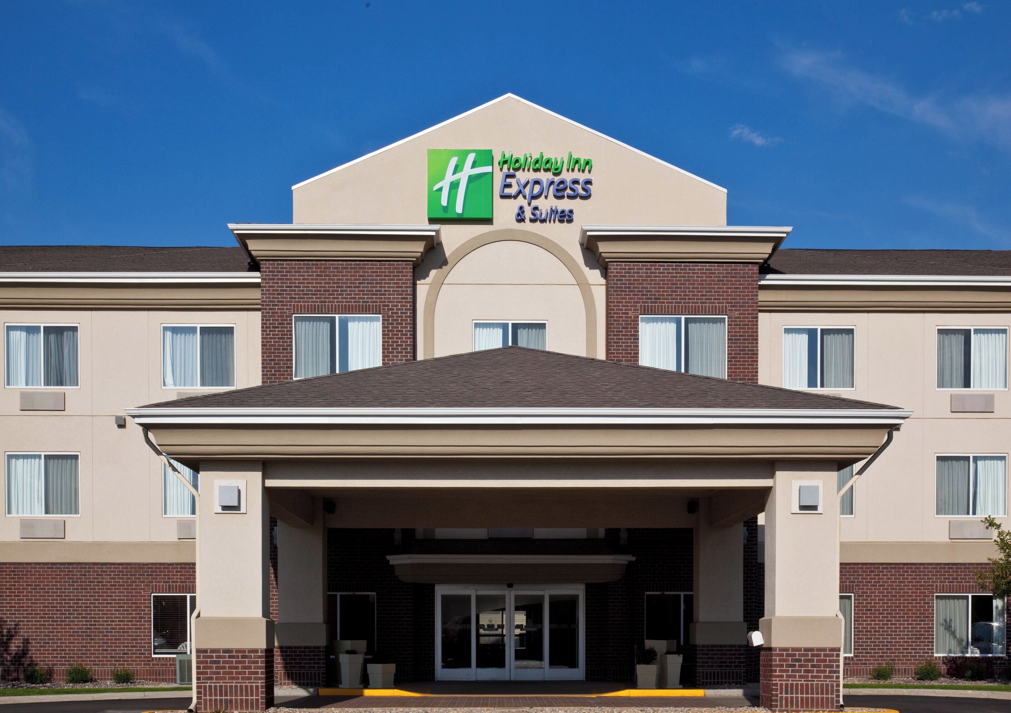 A Holiday Inn Express & Suites hotel with a brick facade, large windows, and a prominent entrance.