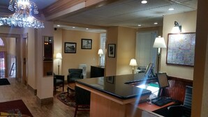 A hotel lobby with a reception desk, seating area, chandelier, framed pictures, and a map on the wall. - District Hotel (Washington)