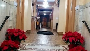 A marble staircase with red poinsettia plants at the top and bottom, leading to a hallway with a wreath on the wall. - District Hotel (Washington)
