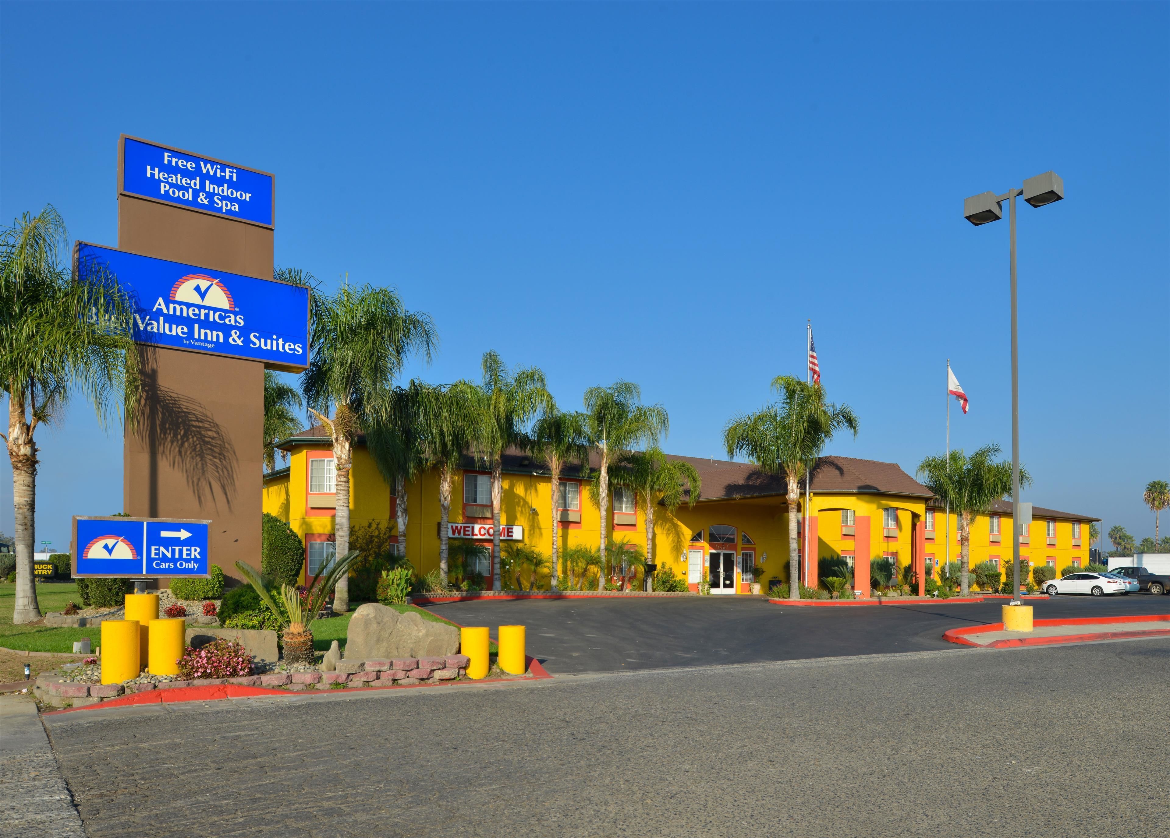 A hotel with a yellow facade, palm trees, and a 'Welcome' sign.