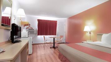 A hotel room with a bed, desk, chair, and a television.