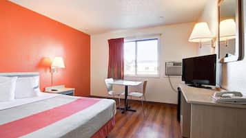 A hotel room with a bed, desk, chair, TV, and window.