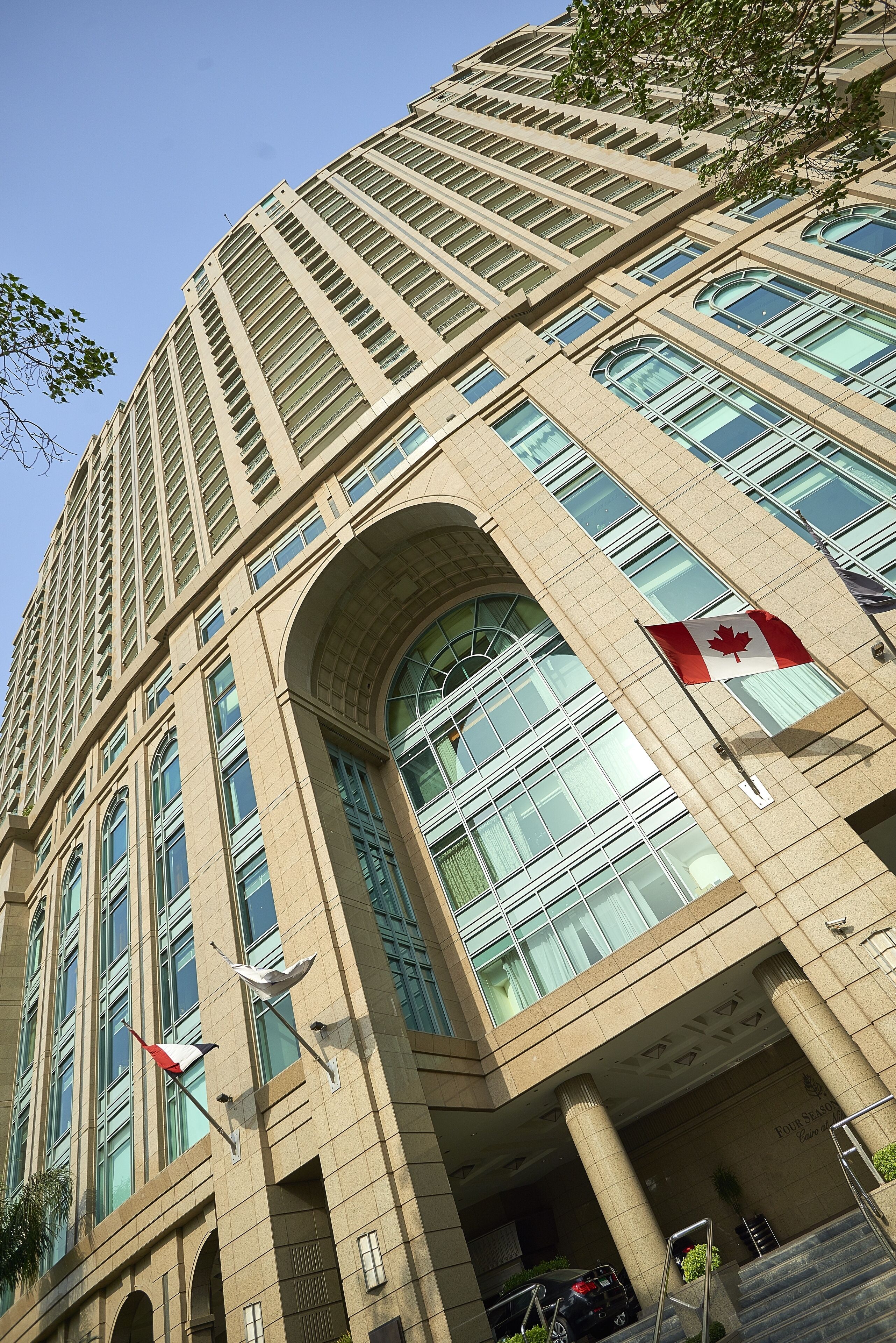 Een hoog, beige gebouw met grote ramen en een opvallende Canadese vlag.