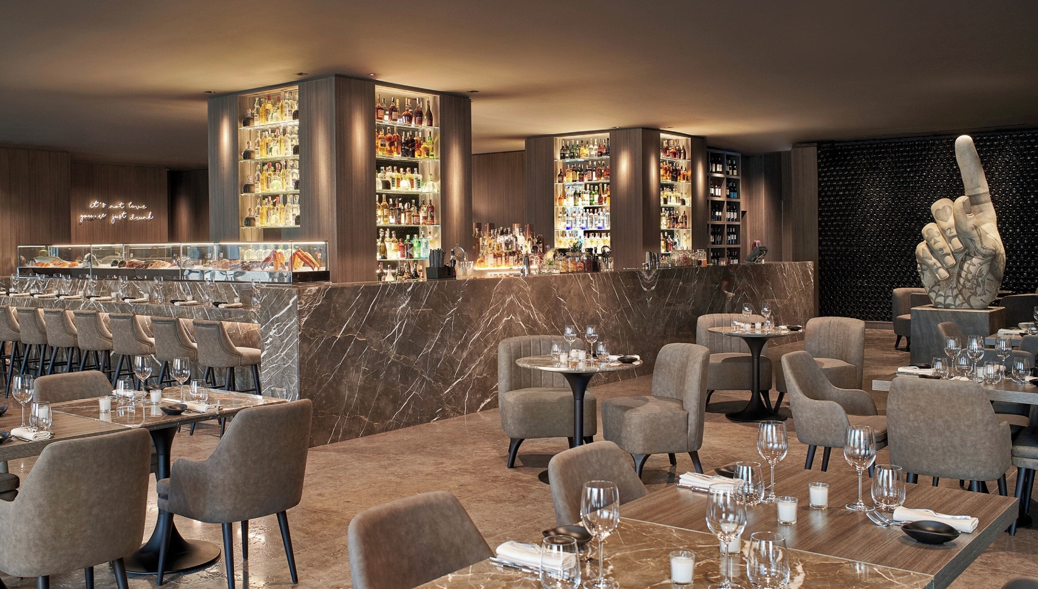 Un restaurante moderno con suelo de mármol, varias zonas de estar y una barra con una amplia variedad de licores.