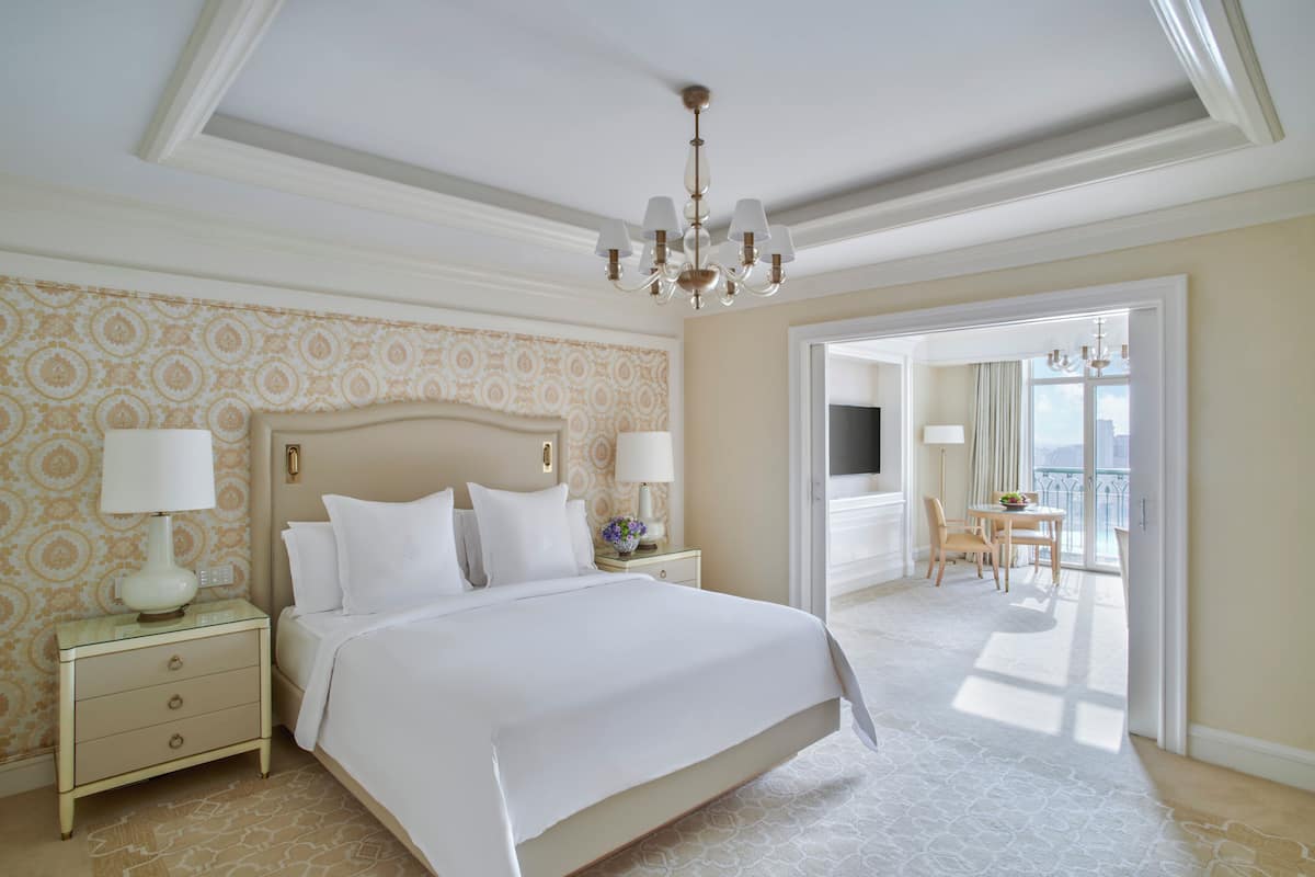 Ein geräumiges Schlafzimmer mit einem großen Bett, einer Chandelier und einem Balkon mit Tisch und Stühlen.