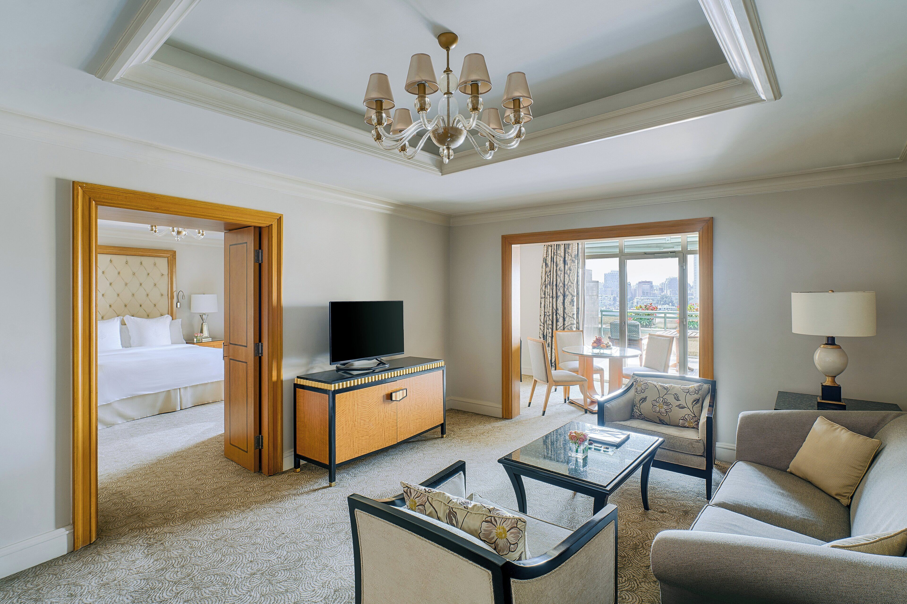 Habitación de hotel con cama, televisión, escritorio, sofá y balcón con vistas.