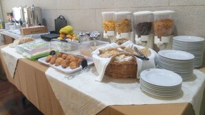 A buffet table with various food items, including bread, pastries, and fruits. - Hotel das Taipas (Guimarães)