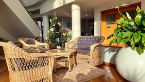 A modern interior with wicker furniture, a Christmas tree, and a large potted plant. - Hotel das Taipas (Guimarães)