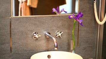 A bathroom with a white sink, a green countertop, and a mirror reflecting a towel and a flower.