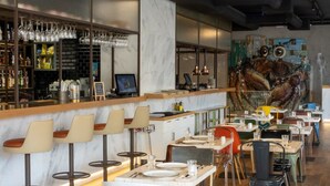 A restaurant with a bar area, bar stools, tables, and chairs. - Internacional Design Hotel (Lisbon)