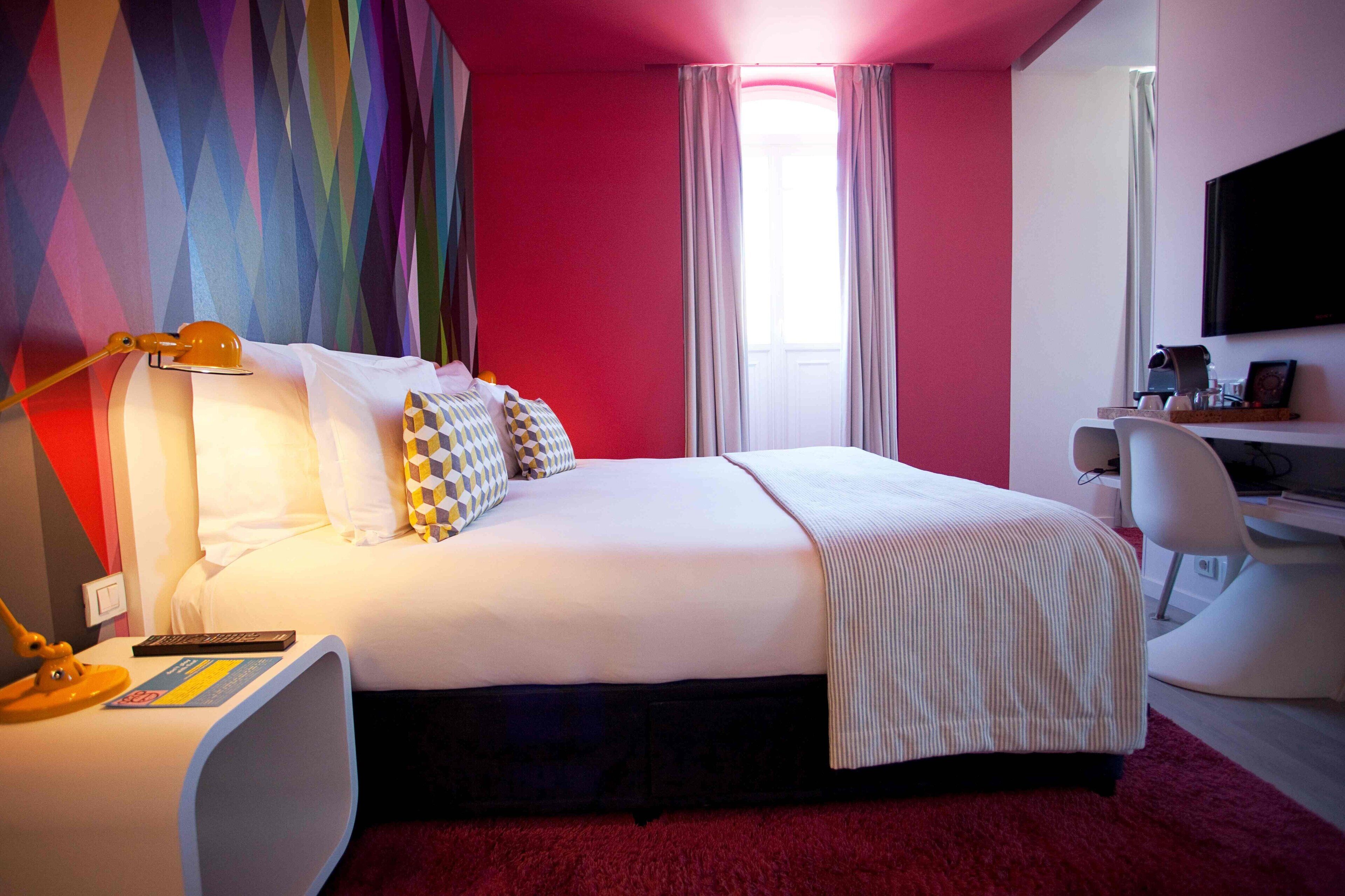 Una camera d'albergo moderna con un letto grande, una scrivania e una televisione.