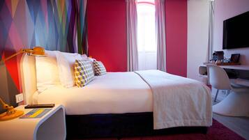 A modern hotel room with a large bed, a desk, and a television.