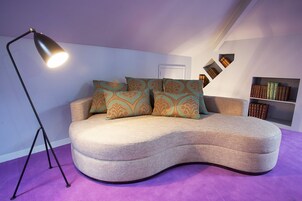 Un dormitorio estilo loft moderno con un sofá curvo, una lámpara de pie y una estantería.