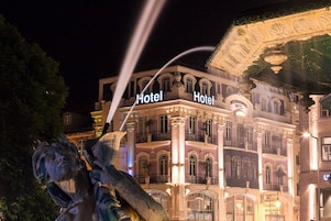 A historic hotel with ornate architecture, including columns and balconies, and a prominent sign indicating it is a hotel.