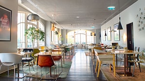 A spacious restaurant with multiple tables and chairs, large windows, and hanging pendant lights. - Internacional Design Hotel (Lisbon)