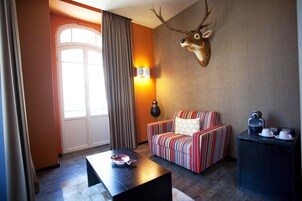 Une chambre d’hôtel avec un canapé à rayures, une table basse, une lampe et une tête de cerf fixée au mur.