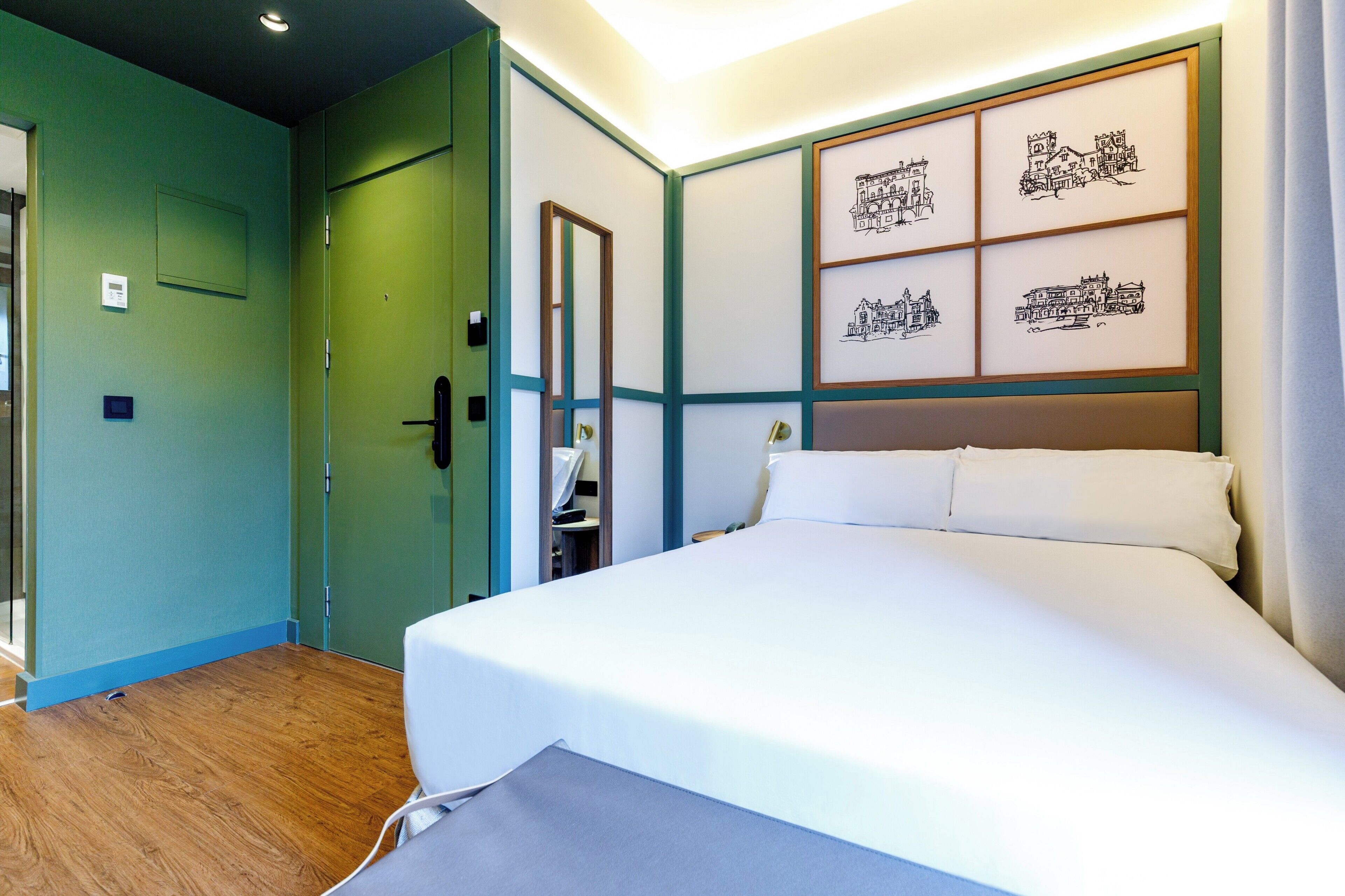 Ein Hotelzimmer mit Bett, Spiegel, Kleiderschrank und Bildern an der Wand.