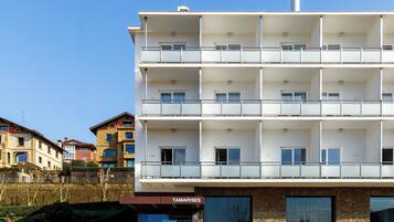 Un hôtel à plusieurs étages, doté de balcons, d’une enseigne indiquant « TAMARISES » et d’une façade en pierre.