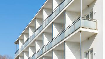 A multi-story building with balconies, large windows, and a clear sky.