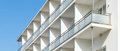 A multi-story building with balconies, large windows, and a clear sky.
