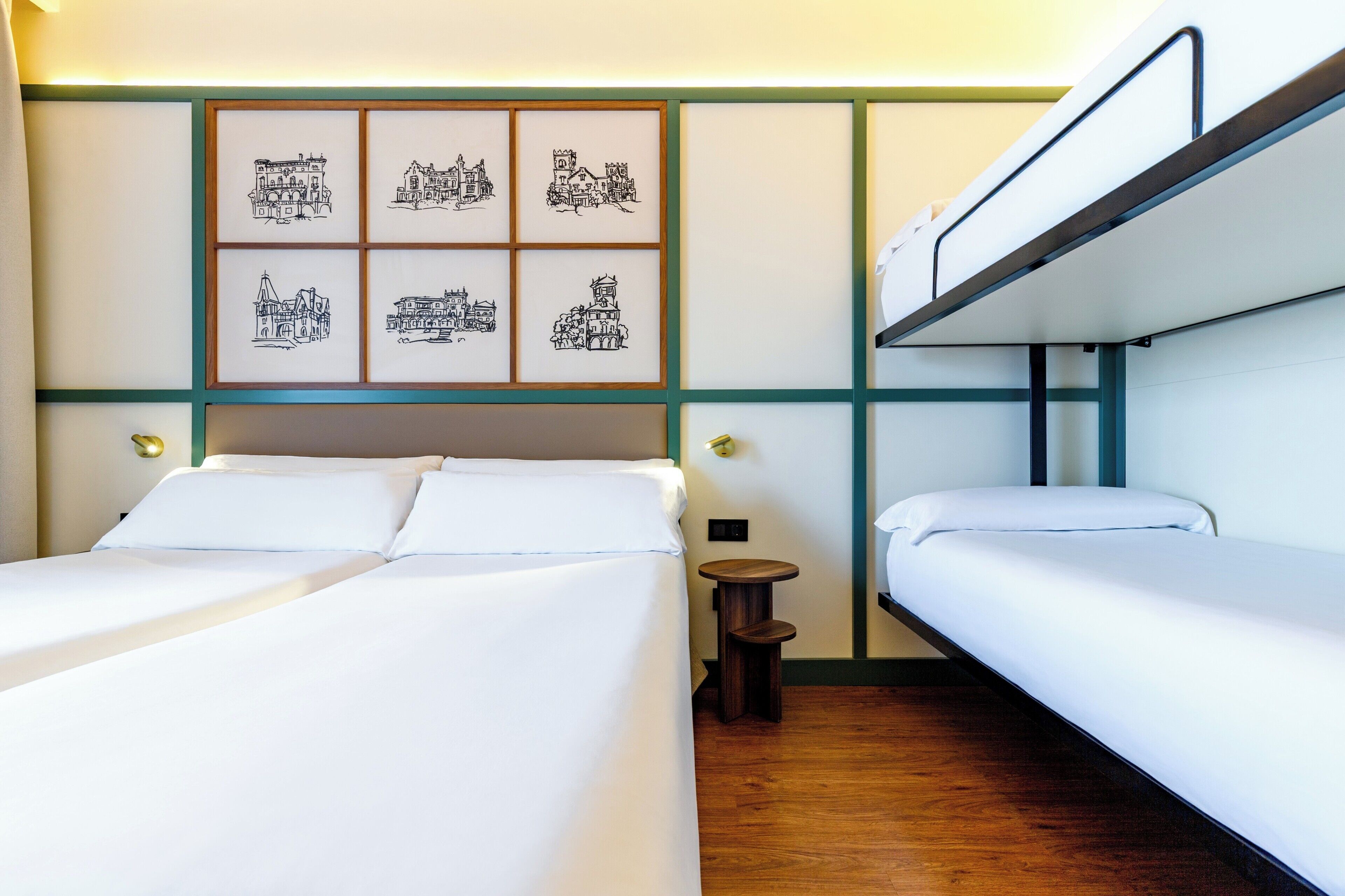 Habitación de hotel con dos camas, un taburete de madera pequeña y una pared con dibujos arquitectónicos blanco y negro enmarcados.
