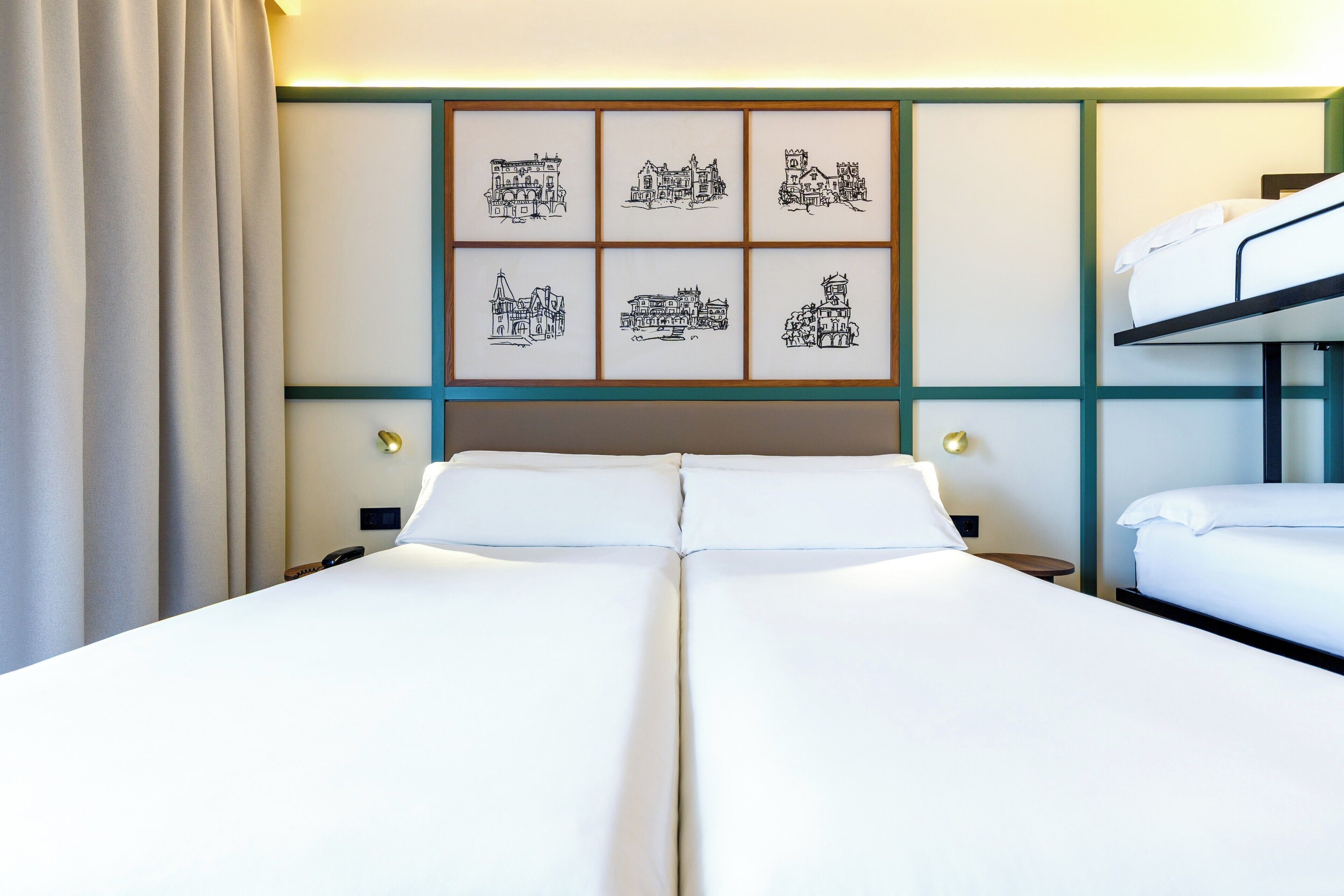 A hotel room with a bunk bed, a large bed, and a wall with framed black and white illustrations.