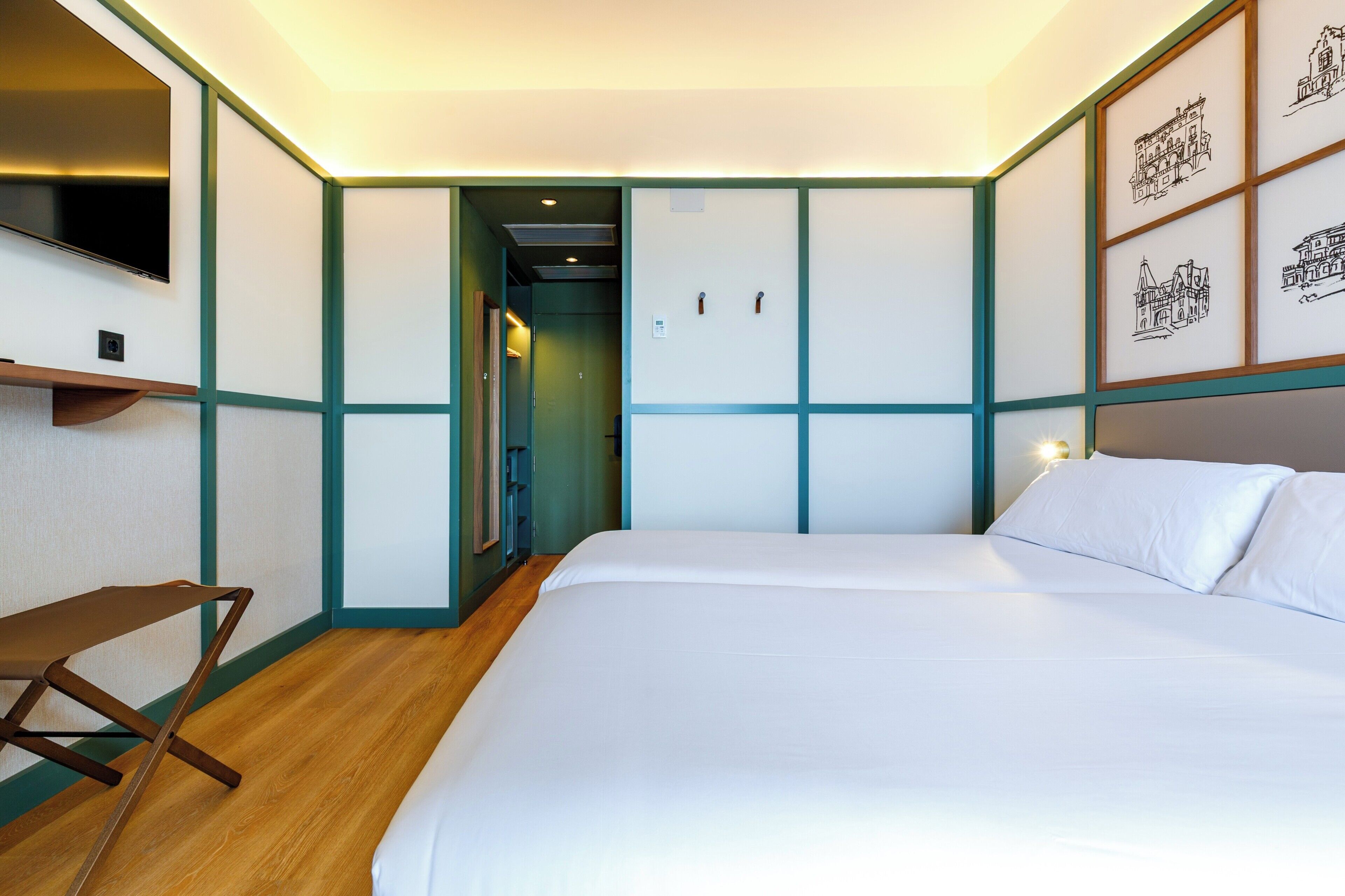 A bedroom with a bed, a desk, and a TV.