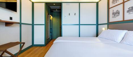 A bedroom with a bed, a desk, and a TV.