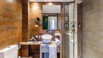 A modern bathroom with a large mirror, a sink, a toilet, and a shower.