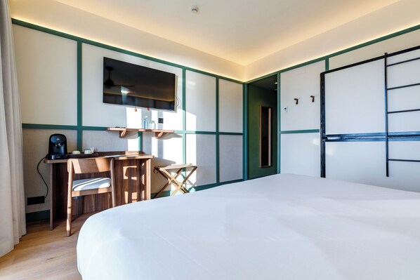 Una habitación de hotel con una cama grande, un escritorio con una silla, un televisor y un armario.