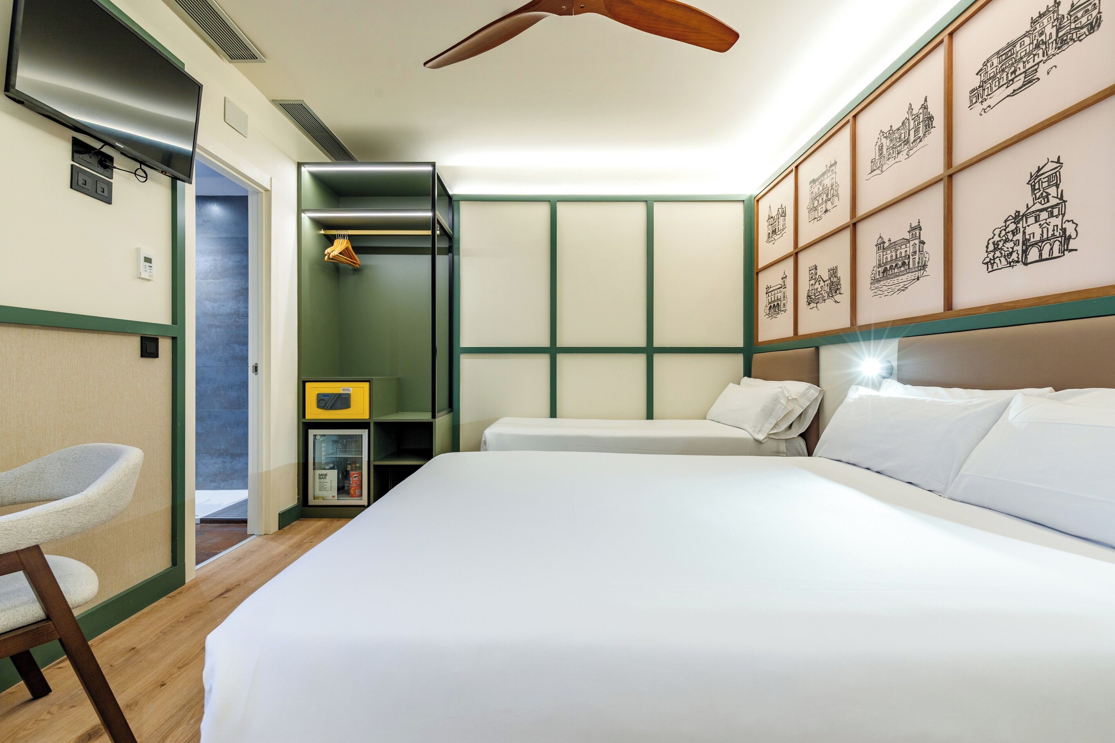 Een hotelkamer met een bed, een stoel, een kledingkast, een televisie en ingelijste foto’s aan de muur.