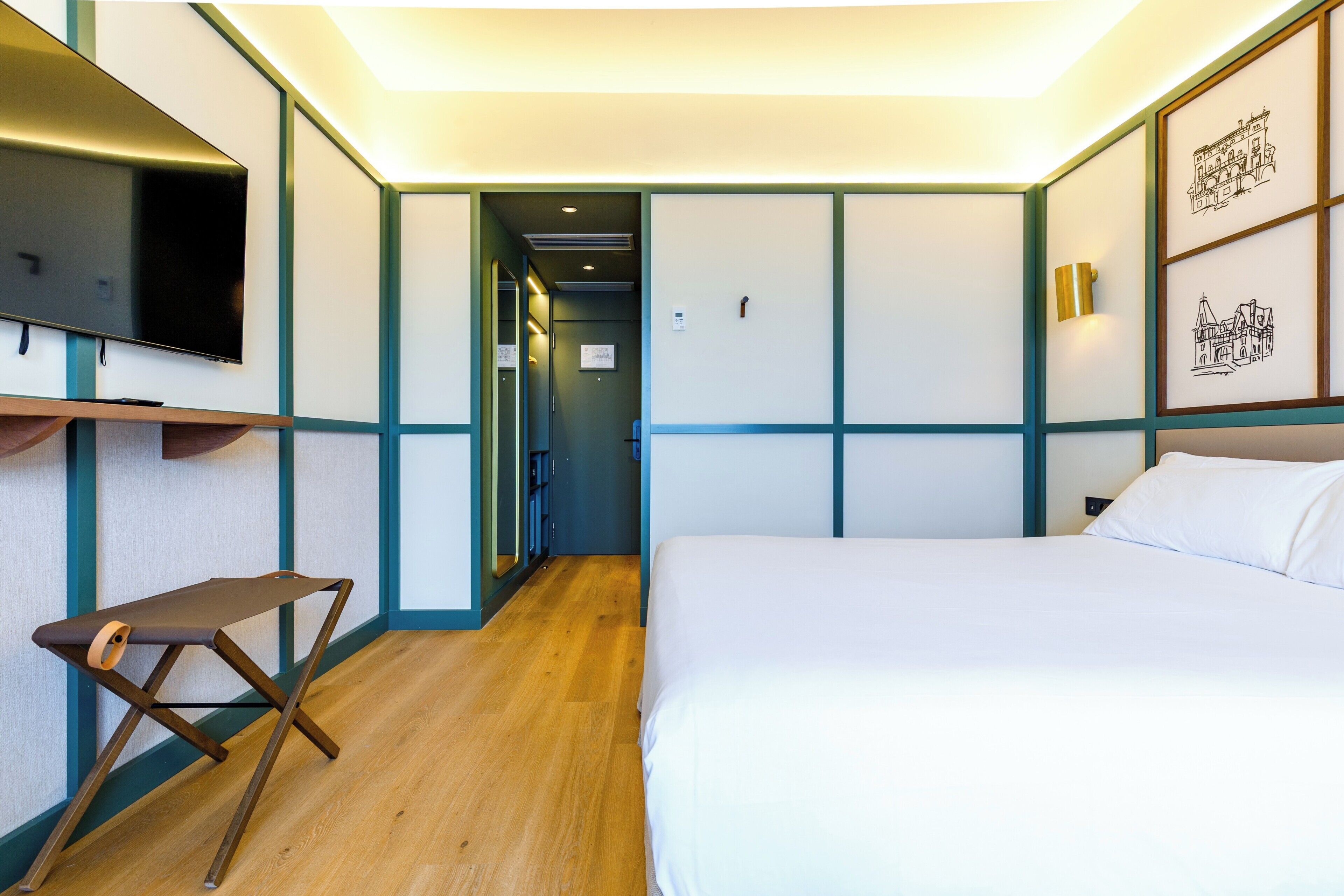 Een hotelkamer met een bed, een aan de muur bevestigde televisie, een bureau en een stoel.